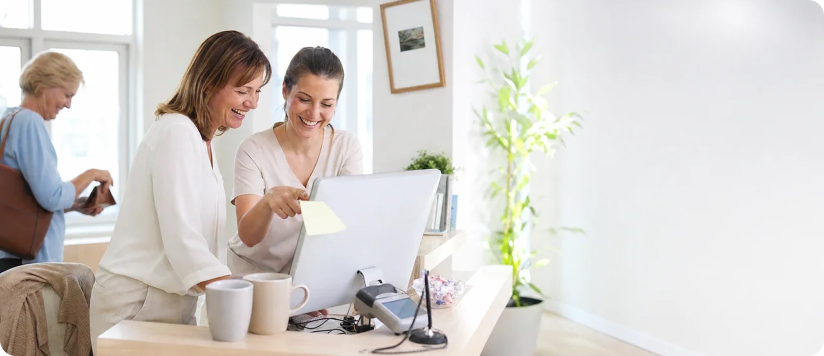A receptionist helping a patient at the front desk
